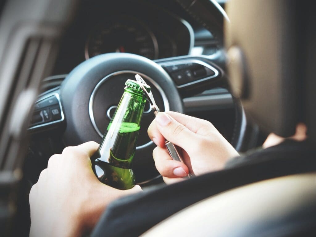 A man drinks alcohol while driving.